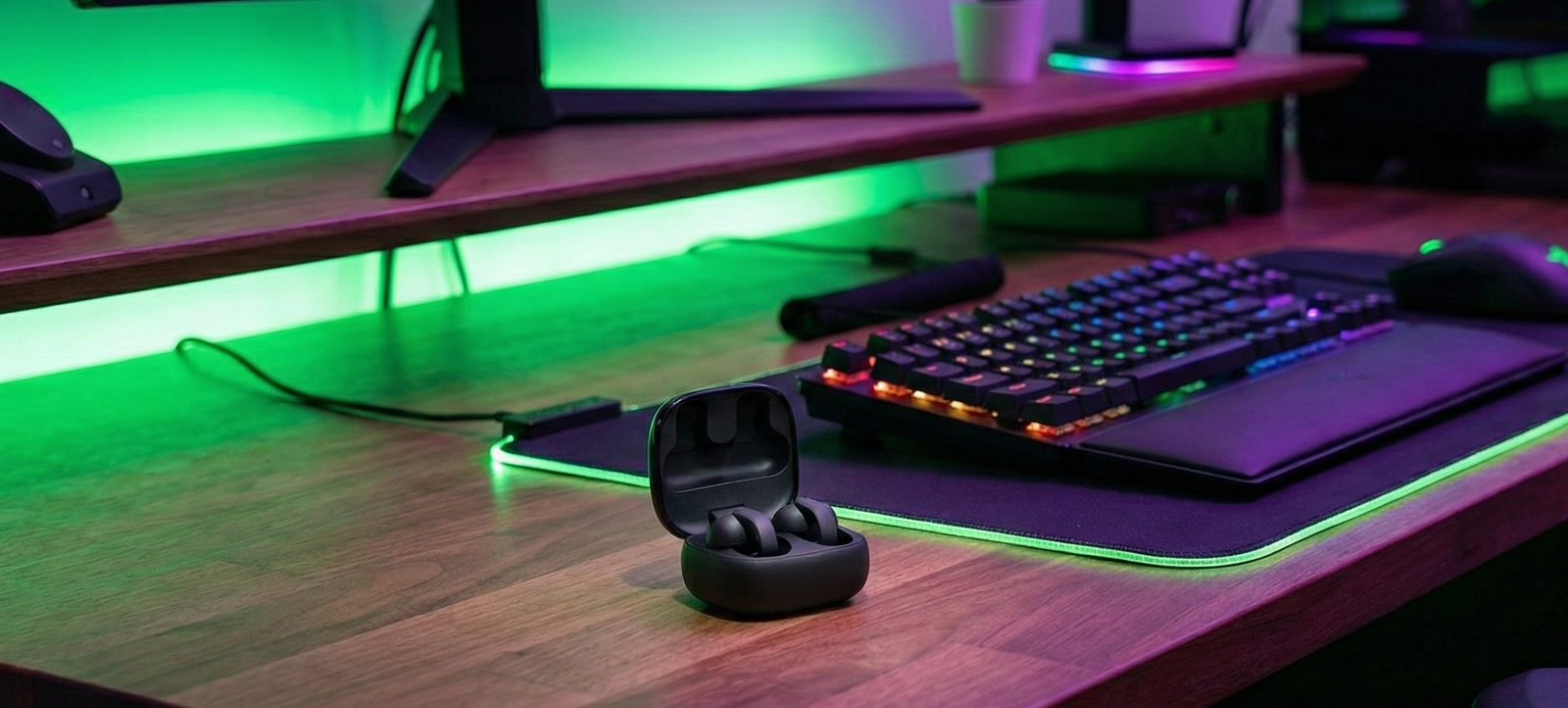 "Auriculares Sony LinkBuds Clip de estilo abierto en color negro, colocados dentro de su estuche de carga abierto sobre un escritorio gamer con iluminación LED verde y morada."